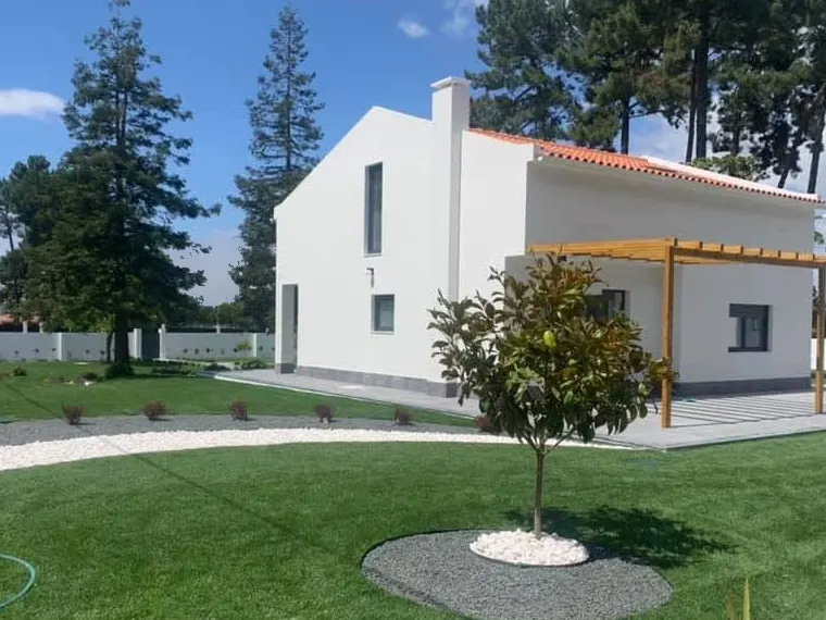 Empena da moradia depois da ampliação, com dois pisos, chaminé e pérgola de madeira.