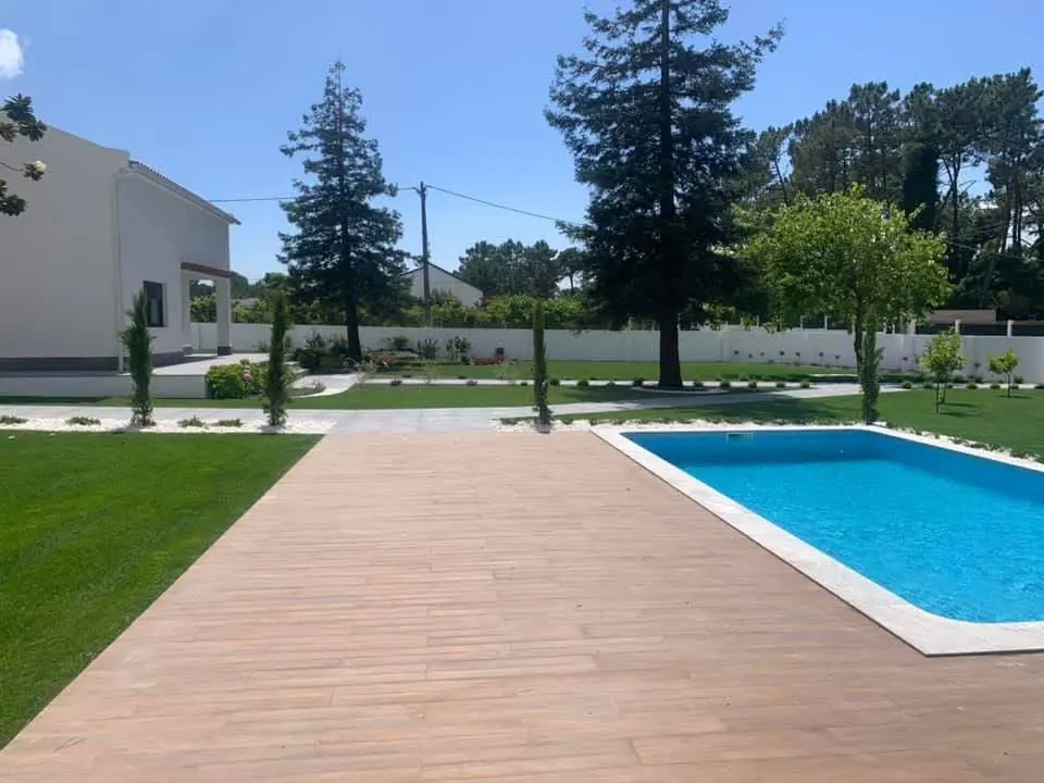 Piscina com deck e jardim com relvado de uma moradia, depois da obra.