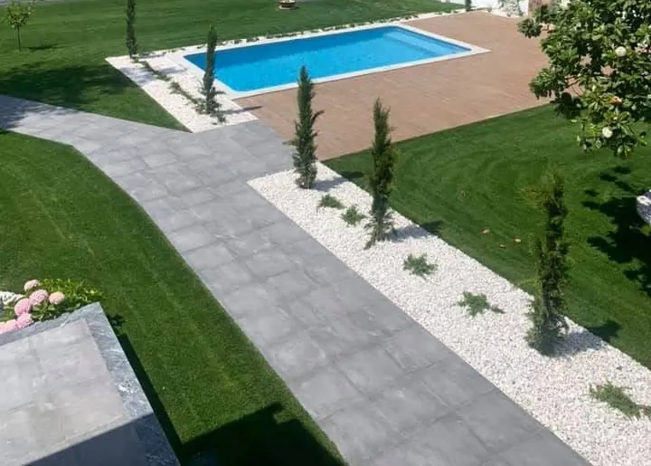 Jardim visto de cima, com caminho em lajeta, gravilha branca, relvado e piscina, depois da obra.
