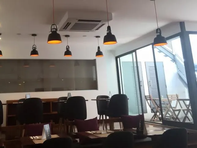 Sala do café depois da obra, com teto falso, candeeiros suspensos e envidraçado para o pátio.
