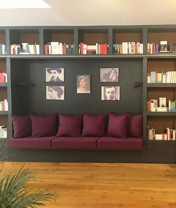 Banco estofado com almofadas entre estantes de livros e soalho de pinho, depois da obra.
